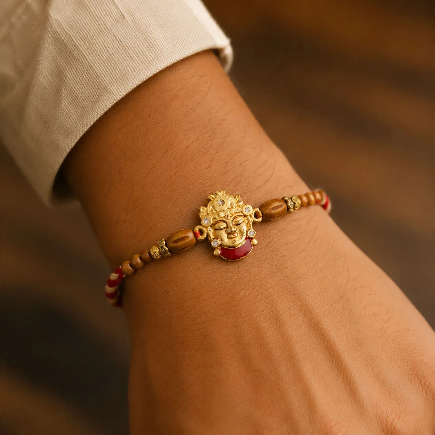 Golden Shrinathji Face Rakhi with Red Enamel Detail, Sandalwood-Finish Beads - Detailed Feature View 2