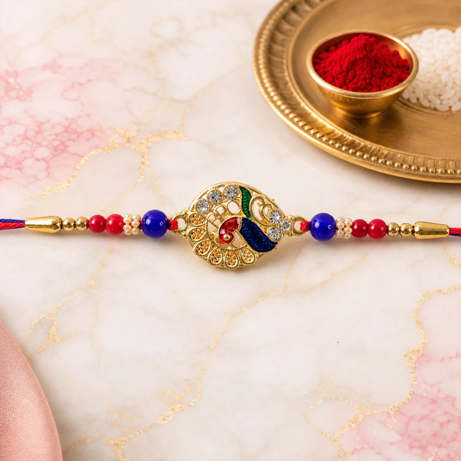 Striking Jewel-Studded Peacock Rakhi Paired with Blue-Red Beads and Tiny Pearls - Detailed Feature View 1