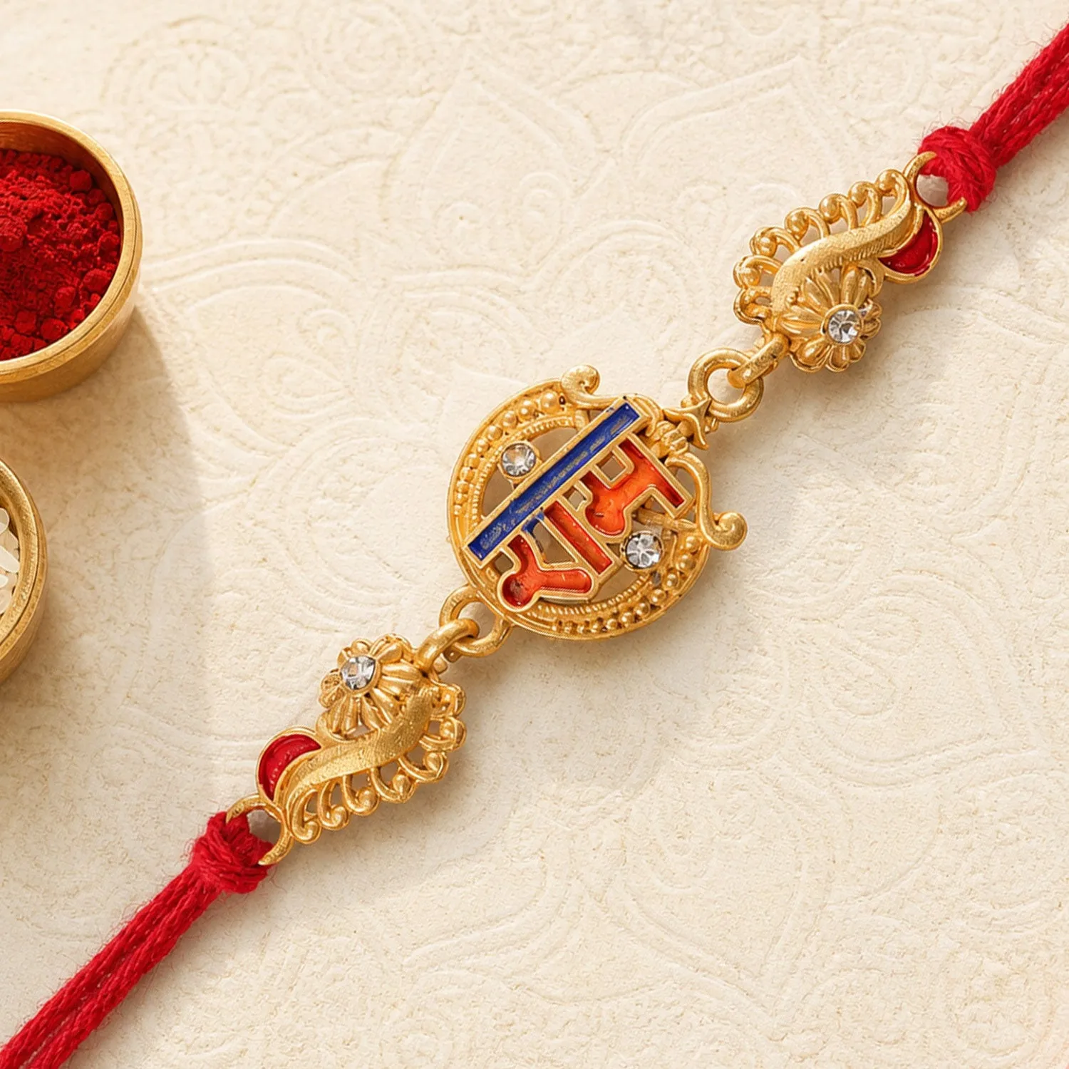 Premium Gold-Toned Ram Rakhi with Orange-Blue Enamel, Crystal Accents & Red Thread - Buy Online at Alikart