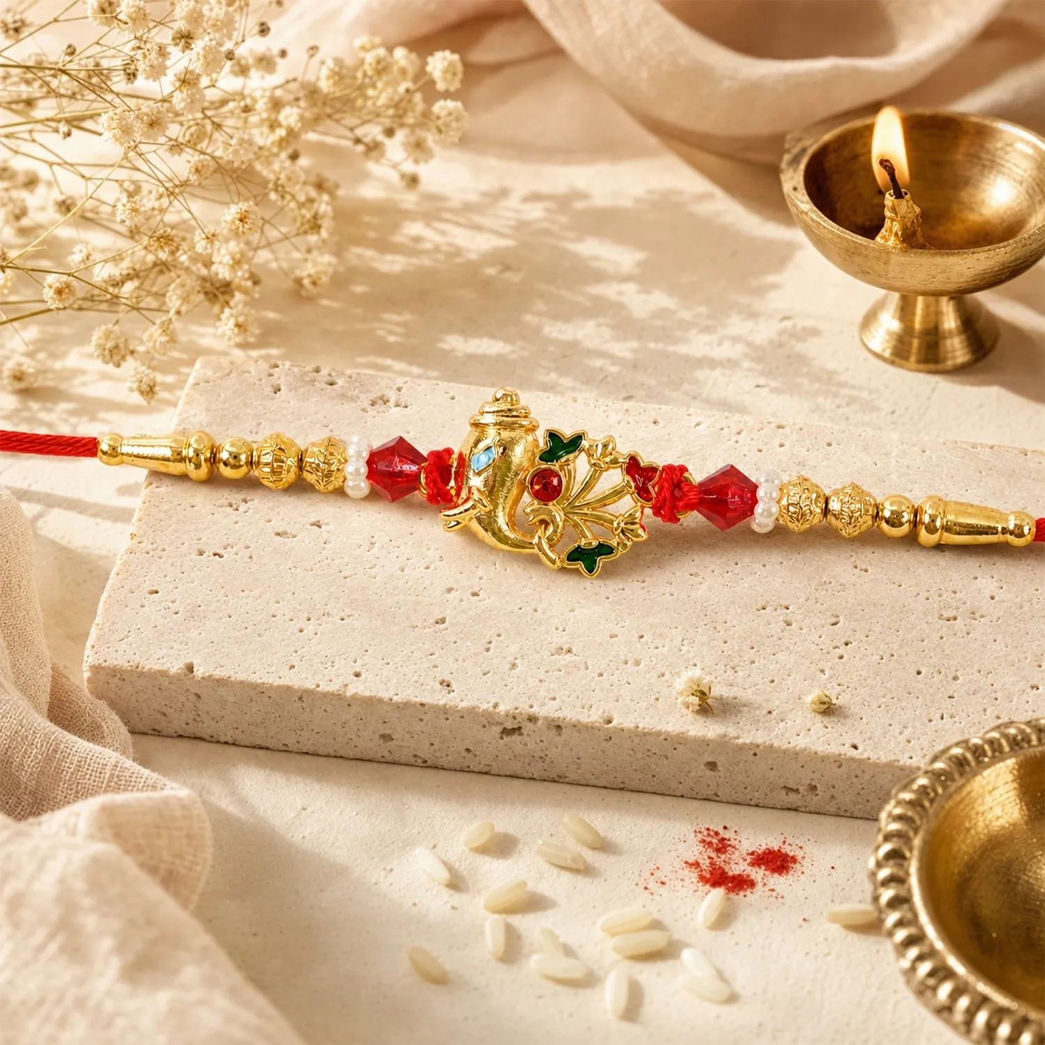 Premium Ornate Lord Ganesha Rakhi Framed by Enamel Flowers, Red Crystals and Pearl Beads - Buy Online at Alikart